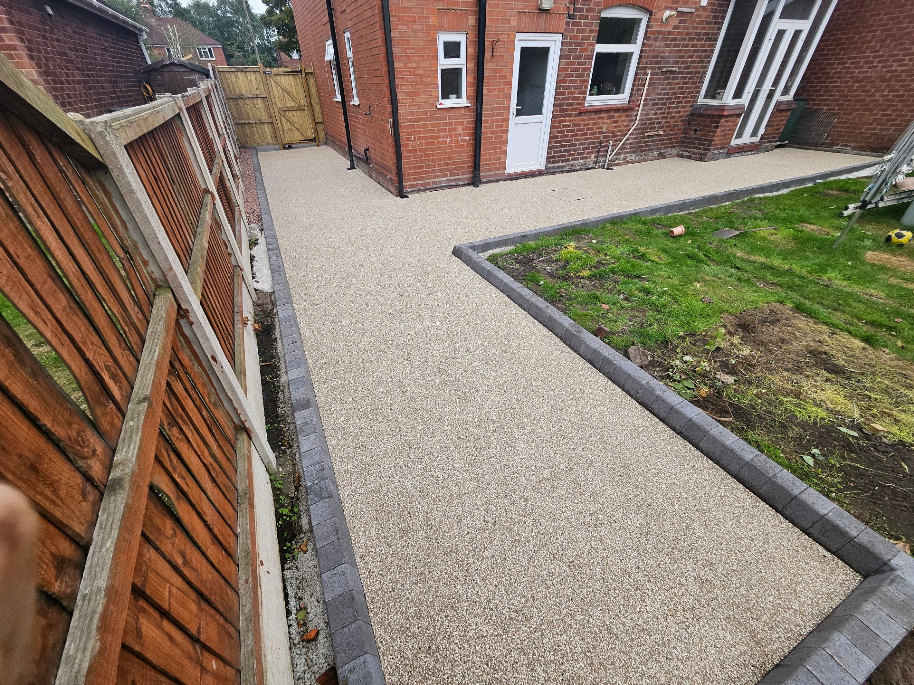 Resin bound patio in Amalfi with a Tobermore Kerb Large (KL) border at the rear of the Elworth house